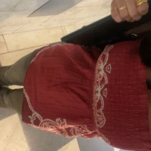 Röd tubtopp med vitt mönster - En röd tubtopp med vitt mönster. Toppen har en smockad överdel och är axelbandslös.