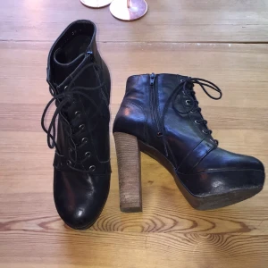  - Svarta kängor med träklack. 
