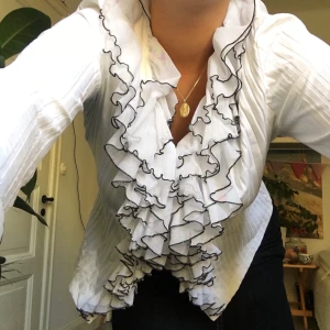 Ruffle tröja/kofta, S-L str, Humana - Vit ruffle tröja/kofta med 3 knappar placerad på övre delen av tröjan för att stänga. Helt oanvänd och köpt på humana, stretchigt material som passar flera storlekar. 