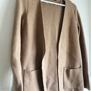 Beige kofta strl XS - Beige lång kofta med en ficka på vardera sida framtill. Storlek XS, men passar även S. 