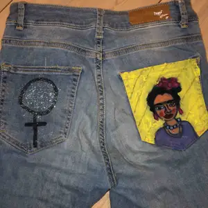 Reworked jeans med Frida Kahlo och kvinnosymbol på fickorna. Storlek XS/S. Frakt tillkommer 