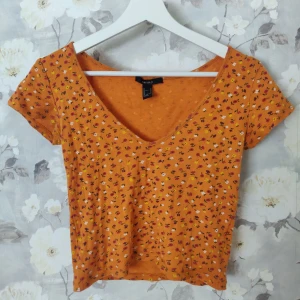 Topp från Forever21 - Kortare topp med djup V-ringning. Jättefint mönster. Färgen stämmer bäst överens på bild 2. Sparsamt använd. Gratis frakt!