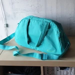 Träningsväska Nike - Smidig, turkos träningsväska från Nike som är helt ny! Har en liten innerficka och en löstagbar axelrem. Köparen står för frakten och jag samfraktar gärna🥰