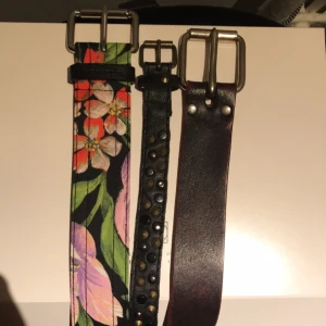  - Tre olika skärp till salu! Ett rödbrunt läderskärp, vintage, 30kr. Ett smalt svart nitbälte, vintage, 10kr. Ett nytt, ej använt blommigt skärp från & other stories, 50kr. (Originalpris 290kr). Alla skärp går att använda som höft eller midjeskärp.  