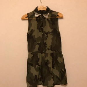  - Byxdress från BikBok med militärmönster. Storlek S. Knappt använd. Krage med paljetter. 100% polyester. Frakt tillkommer!