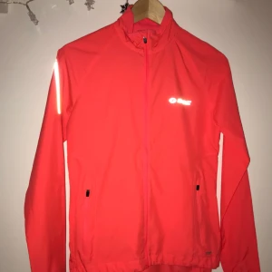  - Löpar/vindjacka från SOC. Väldigt skön att träna i då den är lätt och luftig. Fin korall färg med några reflexer.  