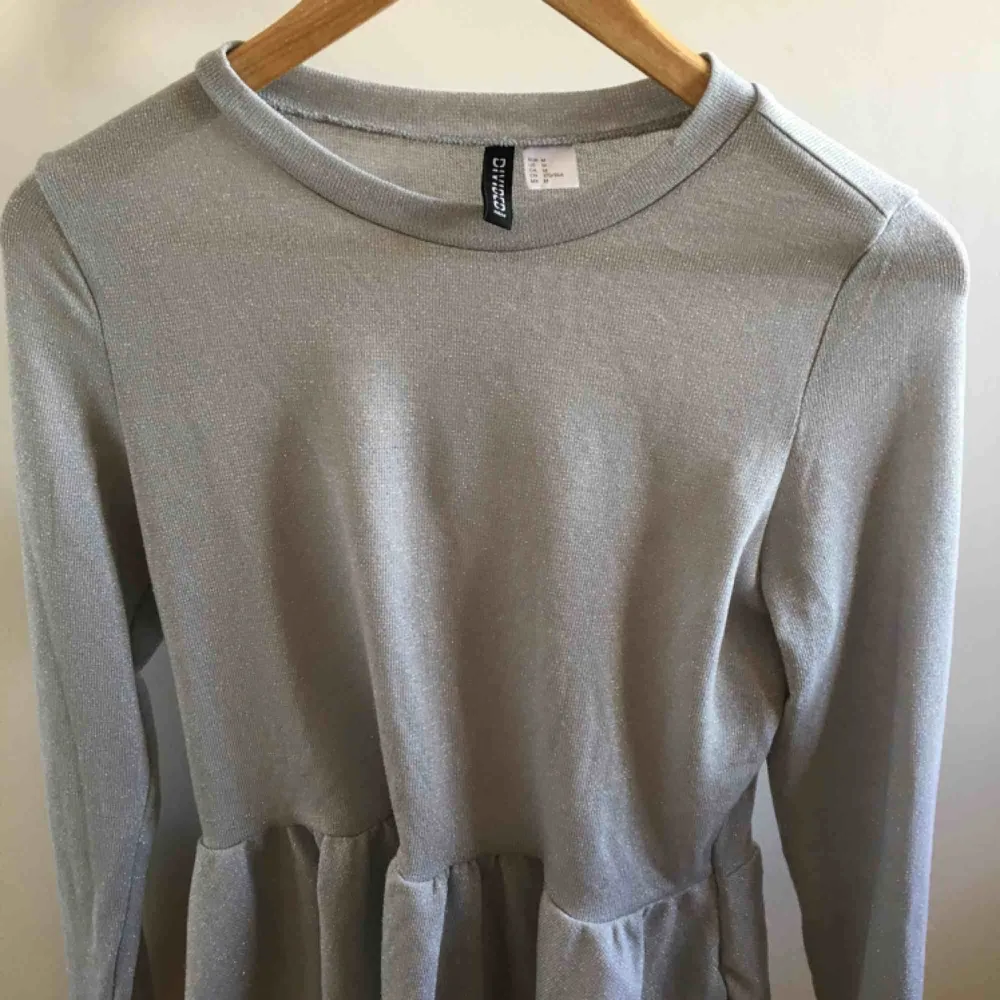 En glittrig grå/ljusblå tröja. Den har en utsvängning längst ner. Inte använd så mycket. Fint skick. Köpare står för frakt. . Tröjor & Koftor.