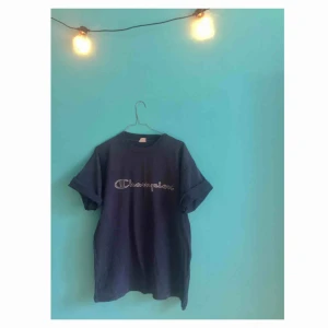  - Mörkblå vintage Champion T-shirt! Uppskattningsvis storlek M/L.  OBS! Blekta fläckar på baksidan av armarna- se tredje bilden!  Avhämtning i Hägersten (kan eventuellt mötas upp i centrala Stockholm). Kan även posta- Då står köparen för frakt.