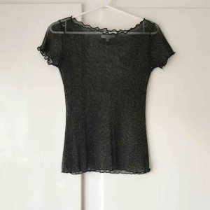  - Guldig och svart glitter meshtopp från Chiquelle. Den har haft ett hål under ena armhålan, vilket jag har lagat. Men såg nu att det har gått upp lite men det är lätt att laga (se andra bilden) Frakt tillkommer med 15 kr. Betalning med swish