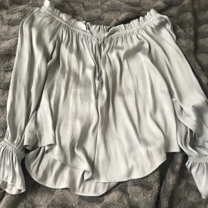 Silvrig blus - Silverfärgad blus från Gina tricot. Off-shoulder och volanger i ärmarna. Storlek S