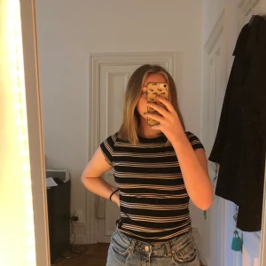 Hm t-shirt  - En svart kort och tight t-shirt med pastell rosa och lila ränder. Str M (divided) men känns som xs 