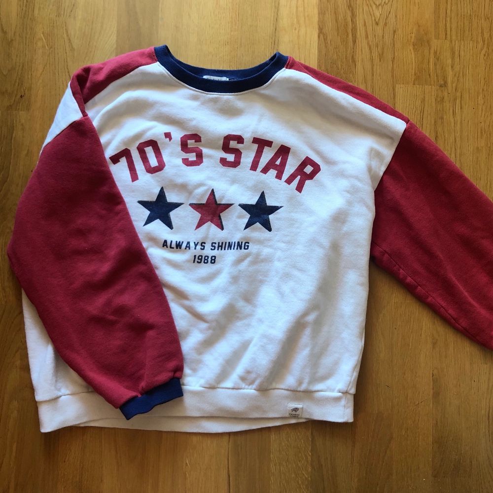 Vit sweatshirt med röda ärmar och blåa detaljer. ”70s star always shine”. Stora mysiga armar, skön inuti. Oversized modell, passar Xs-M. Tröjor & Koftor.