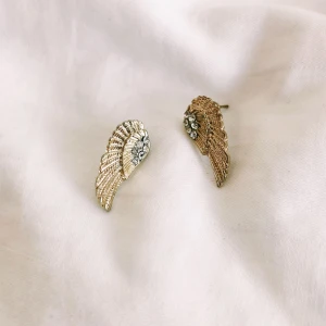 Guldiga örhängen  - Säljer dessa guldiga örhängen föreställande änglavingar för 50 kr då de aldrig används. Vet inte märket eller material dessvärre. Tvättas noggrant med aceton innan frakt, påsen tillkommer! Vid snabbt köp kan pris diskuteras, köparen står för frakt.