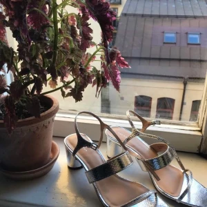 Klackade sandaler i silver  - Silvriga klackade sandaler i strl 39. Fint skick.
