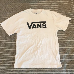 Vans t-Shirt, strl XL junior - T-Shirt köpt på stadium för ungefär 2 år sedan, väl använd men bra skick. Storlek XL junior men sitter som en S. Vit med svart tryck 