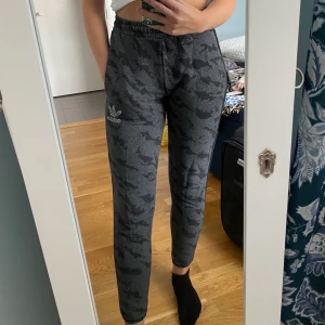 Adidas mjukisbyxor! - Ett par Adidasbyxor i svart militärmönster! Adidasbyxor logan är även i reflex! Jätte mysiga bara inte min stil längre🥰