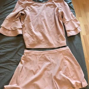 Topp och skjorts  - En fin rosa set med en tröja och skjorts som har volanger på sig. Super fin på och väldigt skönt material. Storlek medium i båda delarna 