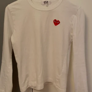 CDG tröja  - Säljer min vita cdg tröja eftersom den blivit för liten för mig. Knappt använd och i jättefint skick. Köpt på NK för 1000kr! OBS väldigt liten i storleken 