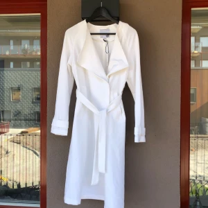  - Lång trench med knytning. Helt ny, tags kvar. 