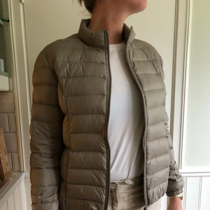  - En tunn dunjacka från Kappahl ”Hampton Republic”. Sparsamt använd. Färgen är mörkbeige/ljusbrun.