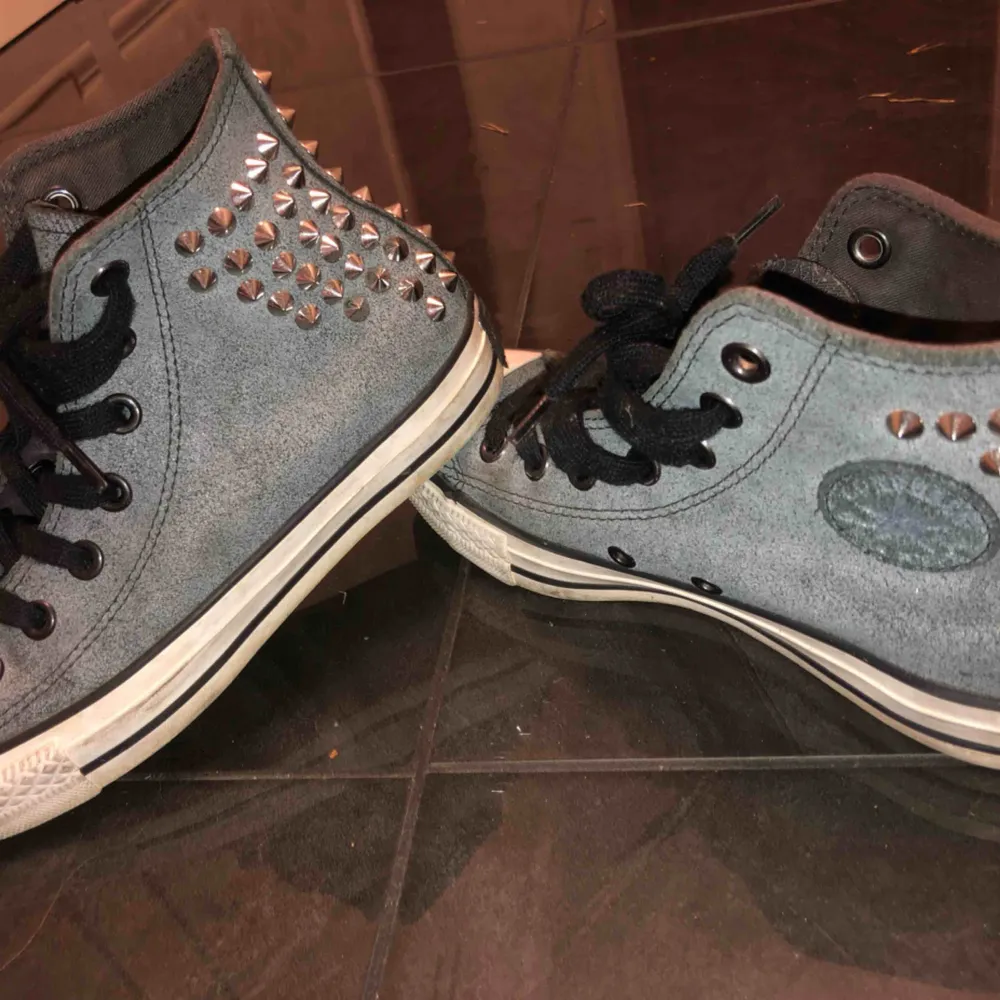 Ett par grå svarta höga Converse med silver nitar bakre delen av skorna, köpta för snart tre år sen men använda bara två gånger. Jättefina, unika och i bra skick!. Skor.