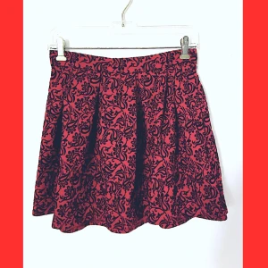 Röd Kjol från Forever 21 - Strl M - Röd midjekjol med svartblommigt mönster från Forever 21 i storlek M (stretch). Har en cirka 20cm lång dragkedja på baksidan och är i toppskick!