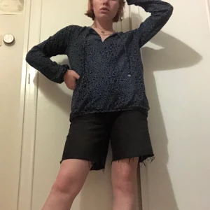 Blå/svart leopard tröja - En blå/svart leopard tröja från House of Lola med snören som har metallcirklar på sig med älvor. Det är resor vid handlederna och längs kanten längst ner. 