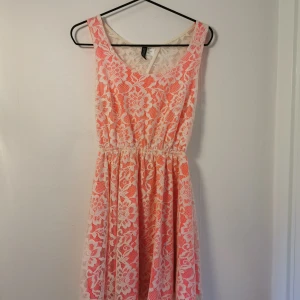 Spetsklänning  - Vit spetsklänning med rosa underklänning. Klänningen är mer neonrosa än vad bilderna visar.