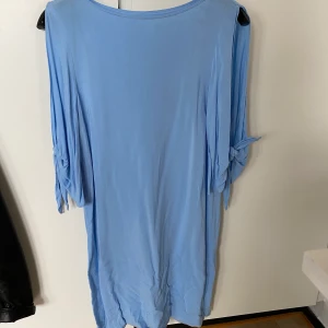 Blå klänning 34 - Ljusblå klänning från H&M strl 34. Klänningen har superfina öppningar på ärmarna som sedan avslutas med en knut. Använd 1 gång så myclet fint skick. Kan fraktas om köparen betalar frakten. Hund finns i hemmet!