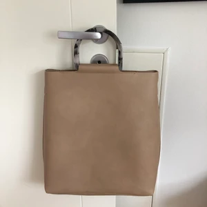 Beige handväska från Carin Wester - Perfekt och rymlig väska för att få plats med dator etc. Hade som skolväska ett tag och är därav i nyskick. Köptes från Åhlens med märke Carin Wester. Band ingår.Frakt ingår ej.