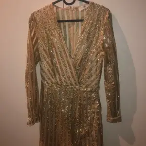 Guldiga glittrig klänning som är köpt på nelly.com.      Använd 1 gång. Perfekt nyårs klänning eller för finare tillfällen! Frakt tillkommer.