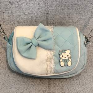 Supersöt Hello Kitty väska i ljusblått. Axelbandet har en liten skråma (bild 3). Skriv till mig vid intresse eller frågor. Frakt: 22kr