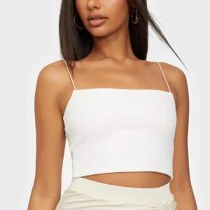 Vit crepe top - Ett vitt linne med ”spaghetti-straps” från Nelly. Storlek S. Fint skick, då den aldrig är använd ! :) (obs! 1:a bilden är lånad från deras hemsida) 