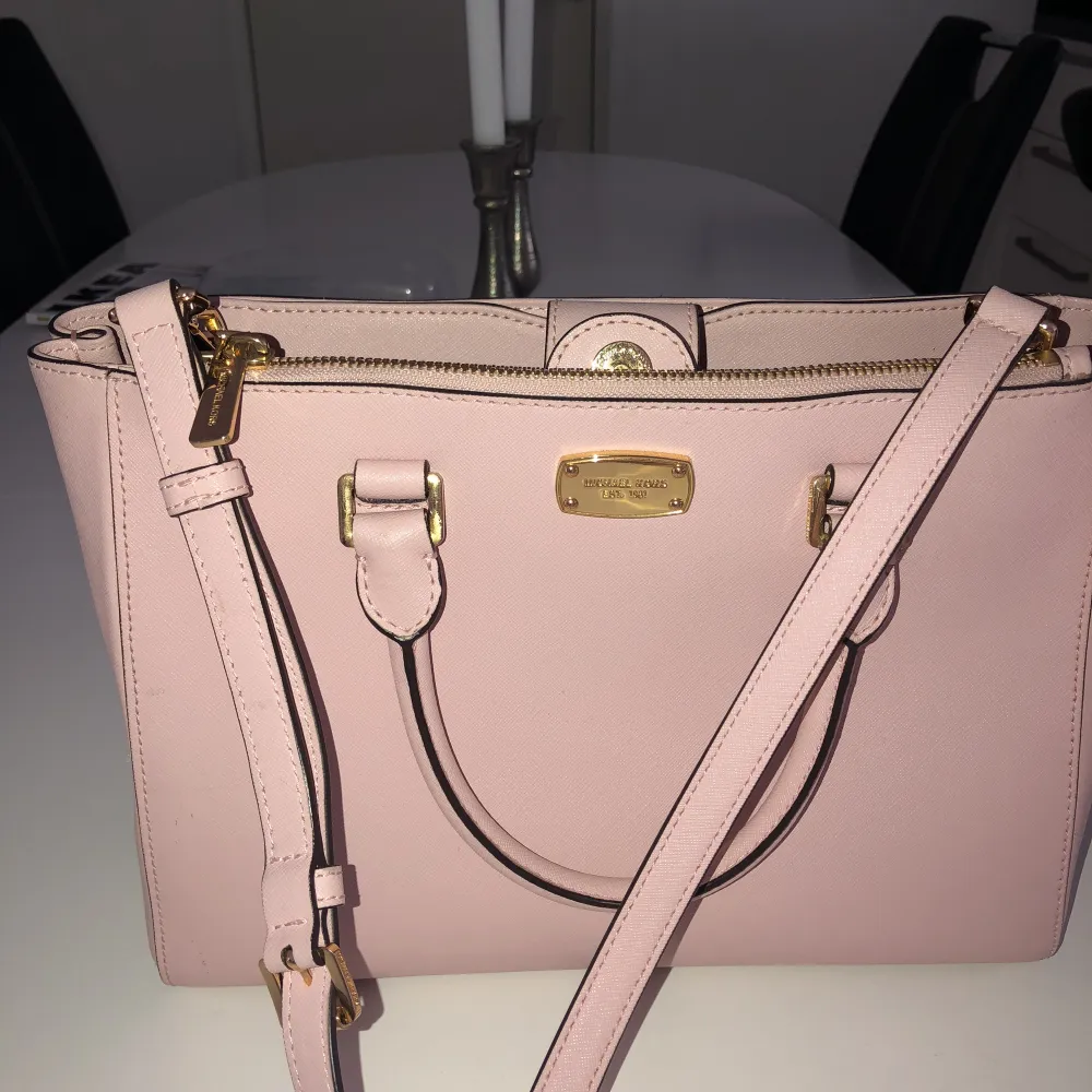 Ljusrosa väska från Michael Kors, en lång axelrem och två mindre handtag. Det långa är avtagbart. Sista bilden visar en liten fläck som finns på baksidan av väskan. Använd ca 2 gånger, och är nästan som ny!. Väskor.