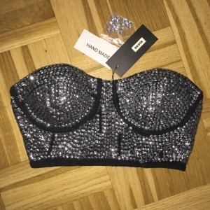  - Bustier S Skimmrande bustier. Silver och svart kombination. Zip på baksidan (se bild 3) Från Bik Bok. Helt ny! Oanvänd! Prislappen finns kvar. Köptes för 299kr! #korsett #bh #glittrar 