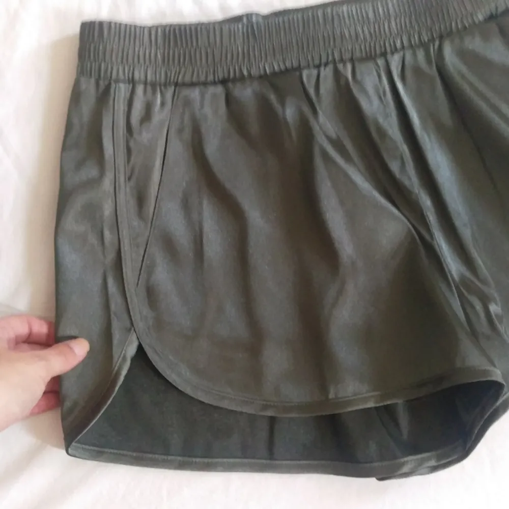 Gröna loungeshorts i glansigt material. Fickor på båda sidor. Aldrig använda. Frakt 30:-. Shorts.