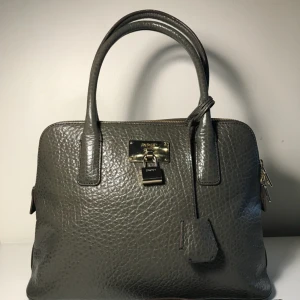  - DKNY Väska, Round Satchel Väska i läder från DKNY i mycket fint skick. Inga märken på användning. Knappt använd!  Färg, Mörkt Grönt  Mått: Höjd: 27 cm           Längd: 37 cm           Bredd: 18 cm