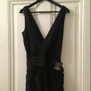 Säljer en LBD, snygg draperad svart klänning från Dry Lake med V-öppning framtill och i ryggen. Oanvänd, prislapparna/tagsen kvar. Dragkedja i sidan. Nypris 500kr.
