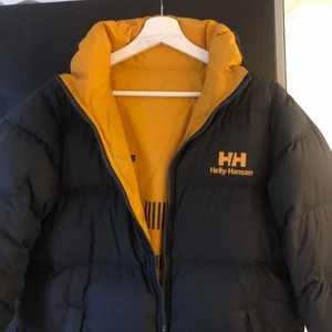 Dunjacka Helly Hansen S - Storlek S. Använd en vinter. Går att ha åt båda hållen. En gul och en mörkblå nästan svart sida. Den gula sidan har blivit lite missfärgad då den färgats av svarta jeans (skriv för bilder). Inga hål eller dun som åkt ut. Nypris 2100. 
