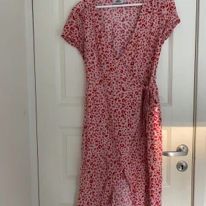 Rosa leopard klänning - Rosa leopard omlottklänning med röda detaljer. Klänningen ifrån ifrån Andrea Hedenstedts kollektion med NAKD.