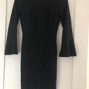 Svart tight klänning - Fin svart tight klänning med utsvängdaärmar som gör över armbågen och en fin djup rygg. Från ginatricot. Går till låten strax innan knäna på mig som är 165. Säljer pågrund av att jag aldrig använder den, har använt den en gång på en begravning men sedan dess har den bara hängt då jag inte använder denna sortens kläder i vardagen💕