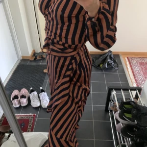 Randig klänning, knälång från MQ - Hjälper mamma sälja sina gamla märkeskläder. Bra skick, knappt använd. Smickrande på kvinnor med större byst. Man väljer själv hur tajt den ska sitta då det finns ett snöre så den kan även passa som M. Inkl frakt