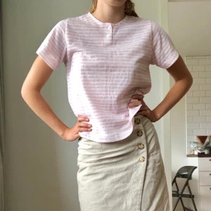 T-shirt  - T-shirt i bomull och polyesterblandning med vita och ljusrosa ränder. Supertunn och sval! Stl på plagget står 42/44 men passar nog både den som är XS och L beroende på hur man vill att plagget ska sitta. 🌸