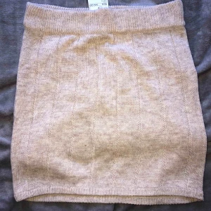 - Mysig stickad kjol i beige färg, helt ny.