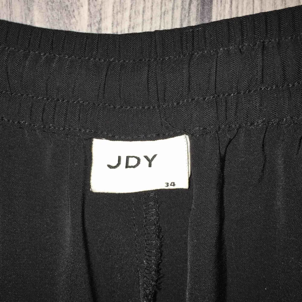 Svarta raka byxor med vit revär från JACQUELINE DE YONG (JDY) i storlek 34. Jeans & Byxor.