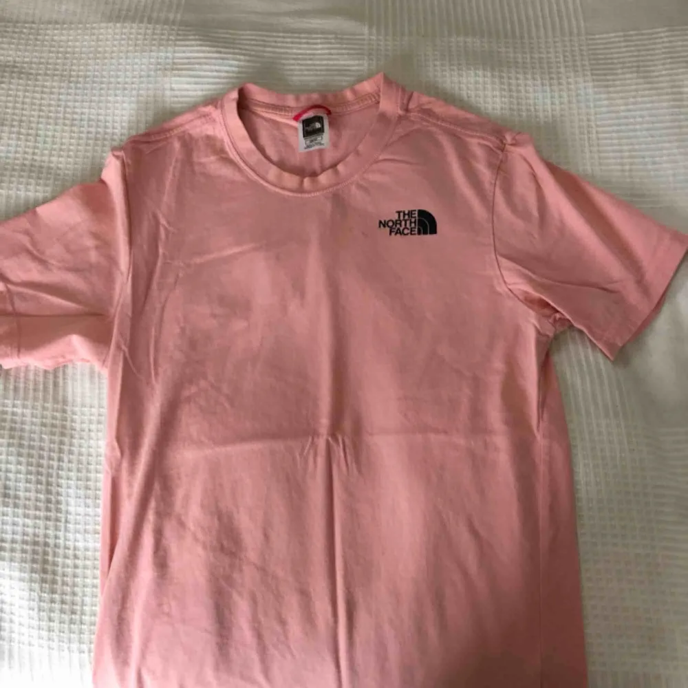 En rosa North Face t shirt med print på ryggen och bröstet. . T-shirts.