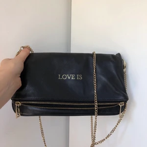 Zadig et Voltaire väska - En super fin limited edition Väska från Zadig et Voltaire i modellen rock. Det står love is på den och en guldig kedja följer med. Man kan ha kedjan i två längder, kors över bröstet eller på sidan (som visas på sista bilden). I jätte fint skick! Fläckfri!  Hör av dig vid fler bilder eller info!
