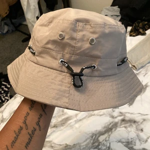 Fiske hatt - En beige fiske hatt skysteringsbar i storlek oanvänd