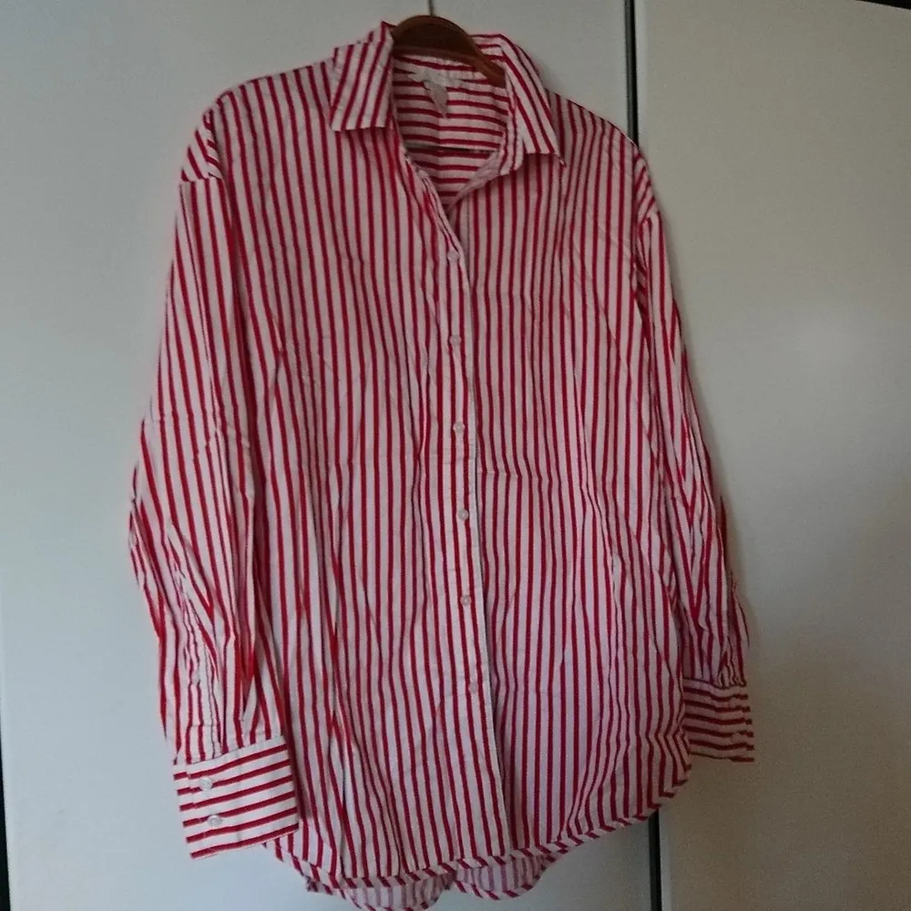 Röd- och vitrandig skjorta i nyskick. Lång modell, lite längre bak än fram. Passar 36-38. Skjortor.