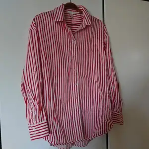 Röd- och vitrandig skjorta i nyskick. Lång modell, lite längre bak än fram. Passar 36-38